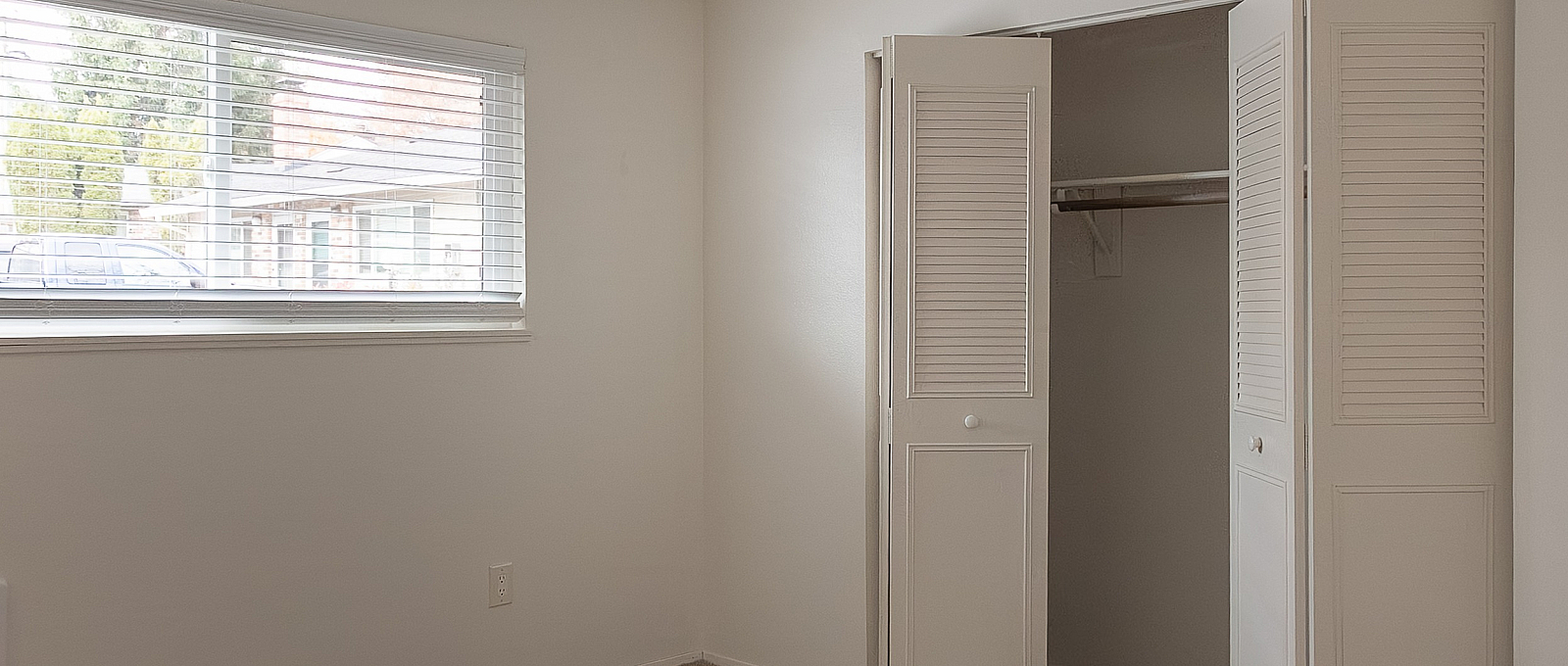 Bright and cozy bedroom with a large window and spacious wardrobe, offering ample natural light and storage.