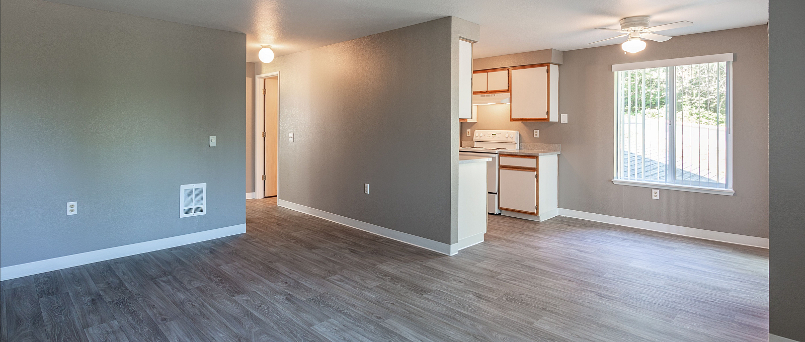 Bright and spacious open-floor layout featuring sleek hardwood floors, modern kitchen with ample cabinetry, and a window-lit dining area.