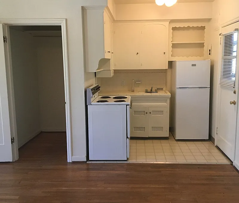 Charming kitchen with vintage cabinetry, sleek white appliances, and warm hardwood flooring.