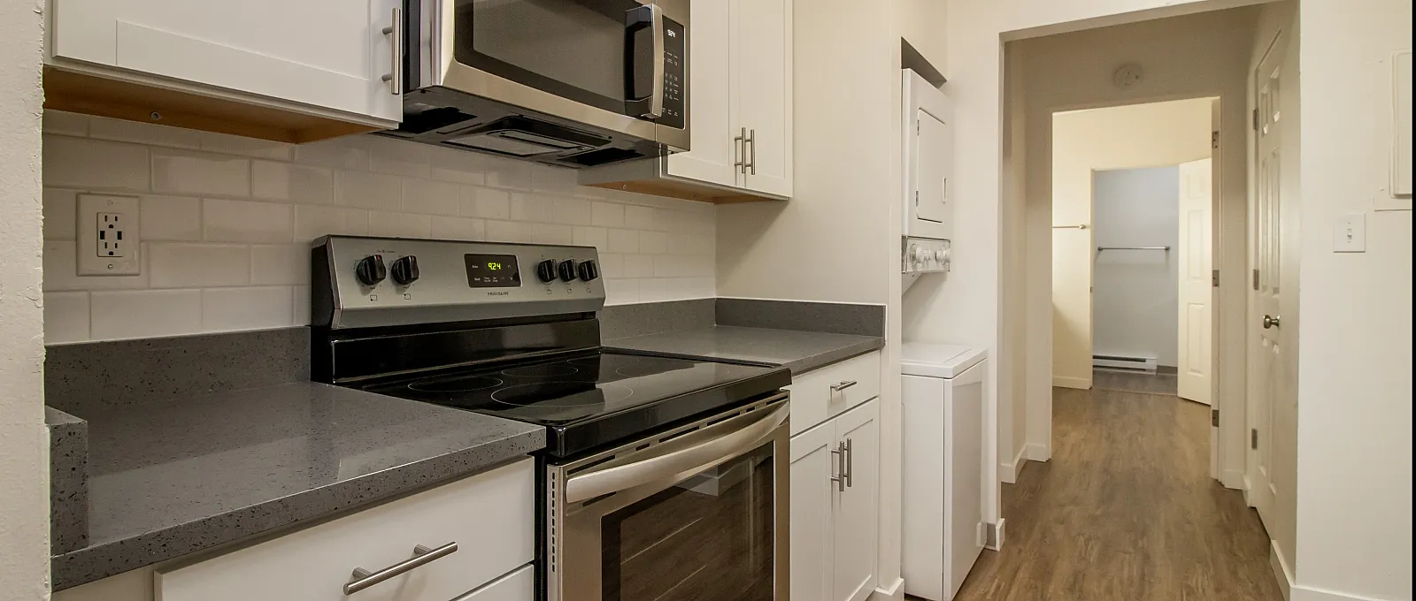 Modern kitchen with elegant white cabinets, sleek stainless steel appliances, and warm wood flooring.