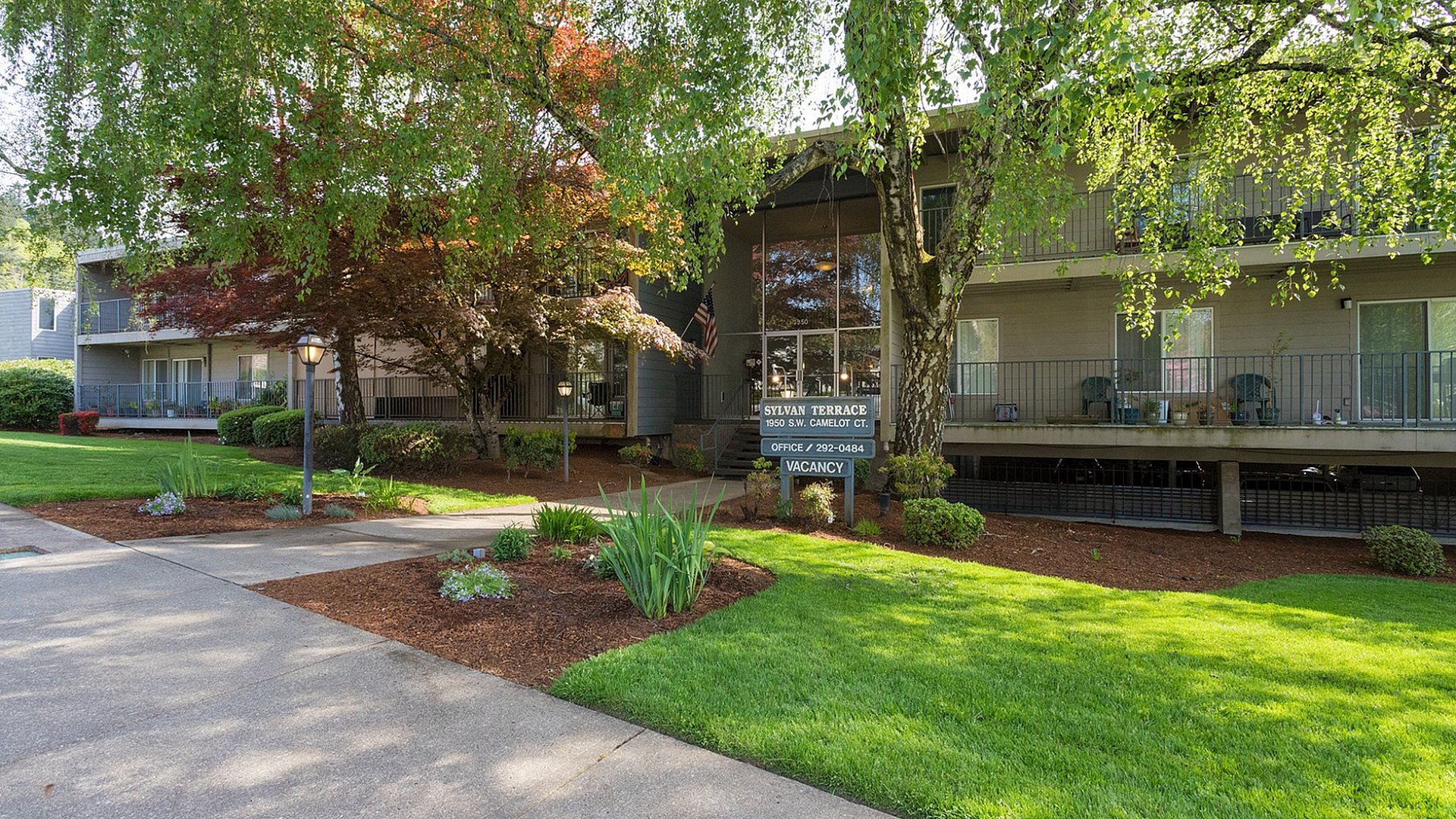 Charming apartment complex surrounded by lush greenery, showcasing Sylvan Terrace's inviting exterior and serene landscaping.