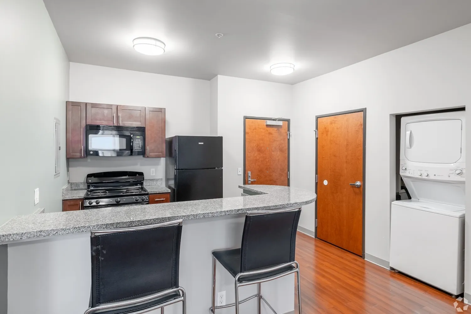 Modern kitchen featuring a sleek breakfast bar, stainless steel appliances, and convenient in-unit washer and dryer.