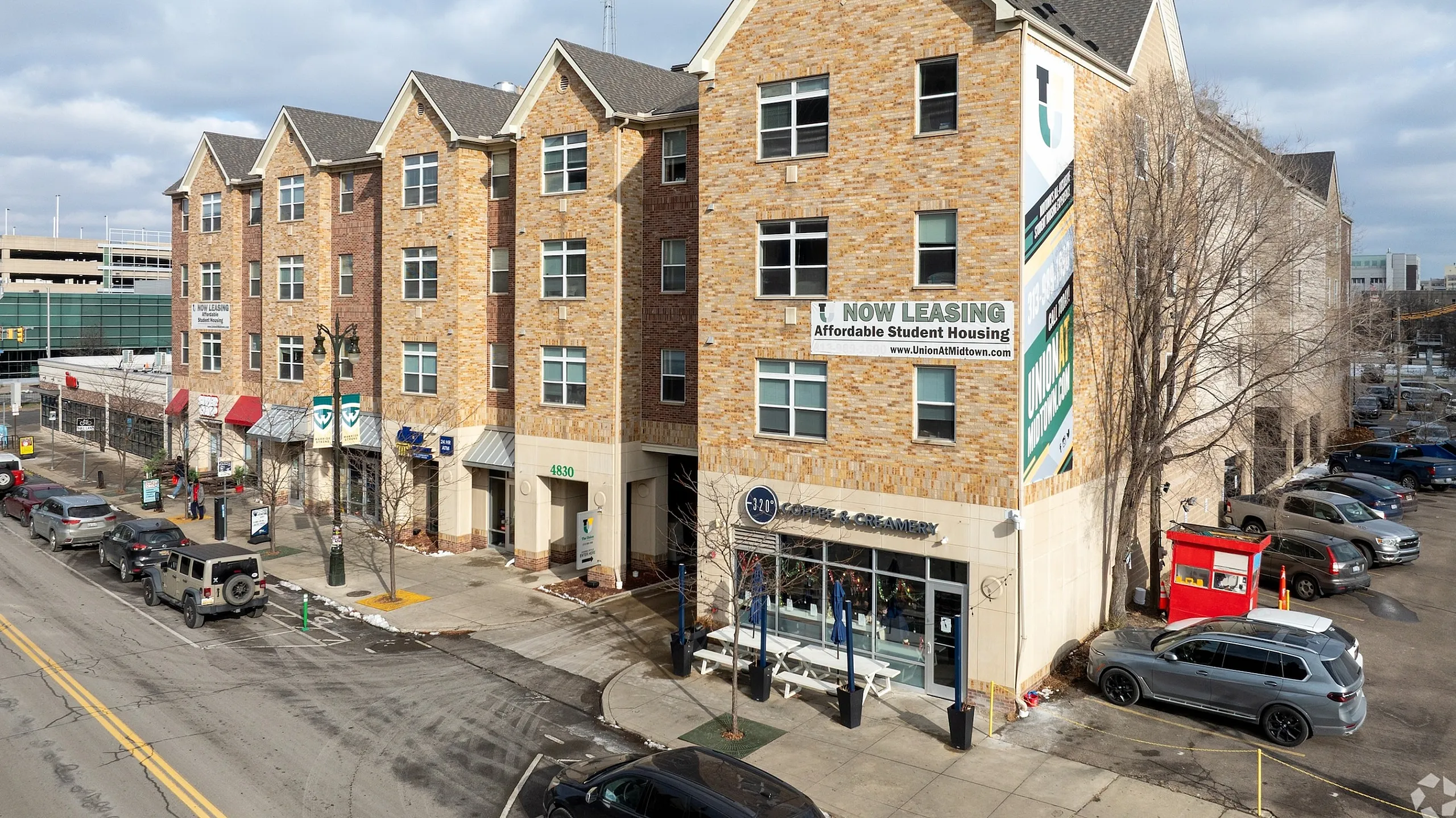 Modern apartment building exterior with charming brick facade, offering affordable student housing; convenient urban location with nearby amenities.