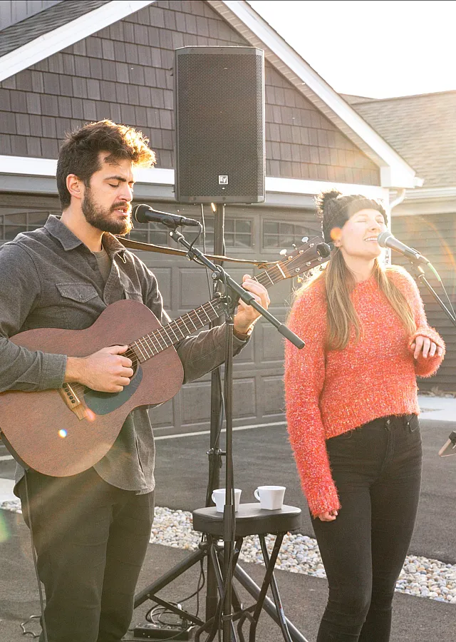 Outdoor music performance with a guitarist and singer in a cozy neighborhood setting.