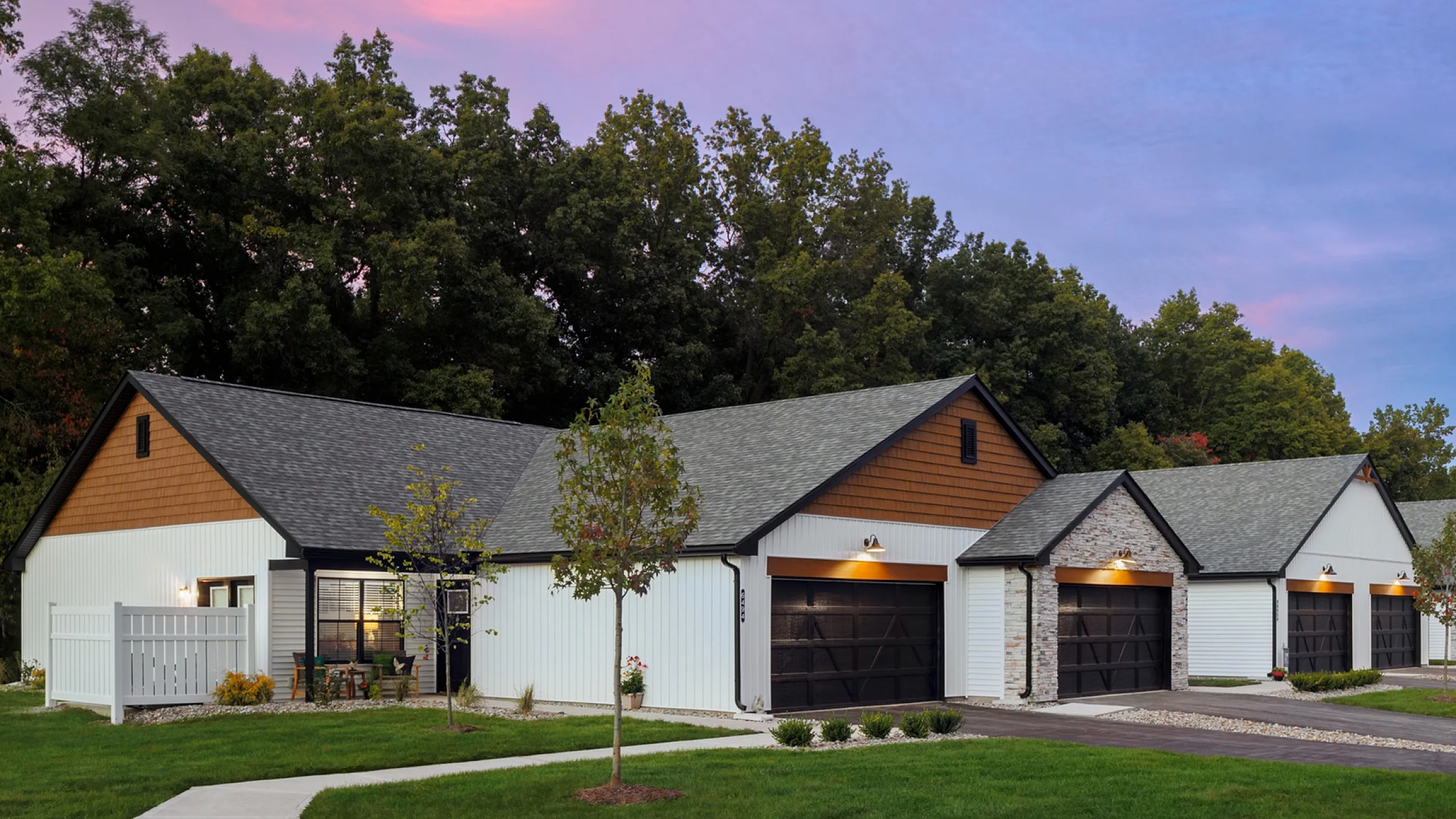 Charming suburban homes with modern design and lush green surroundings, set against a picturesque sunset sky.