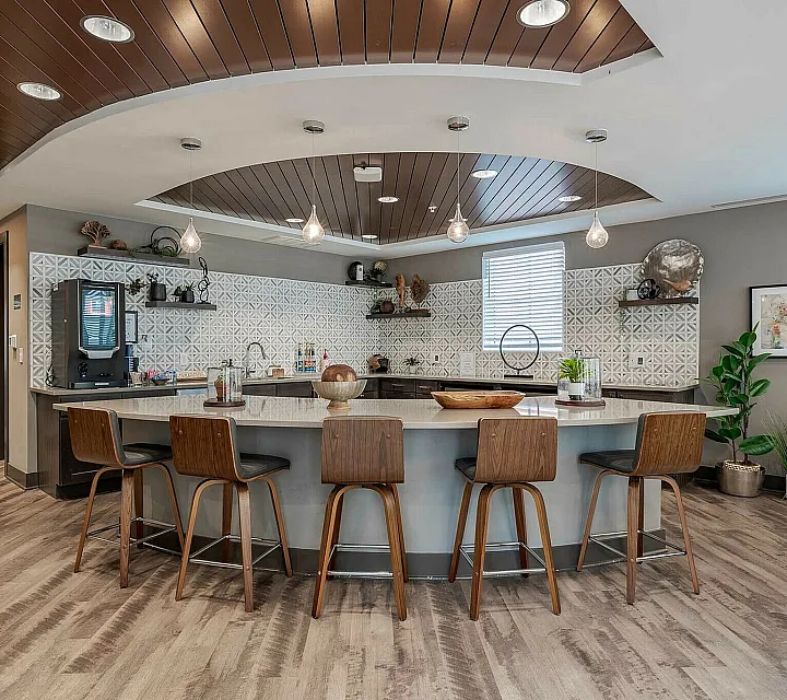 Modern communal space with stylish pendant lighting, elegant bar seating, and a chic tiled backsplash creating a warm, inviting atmosphere.