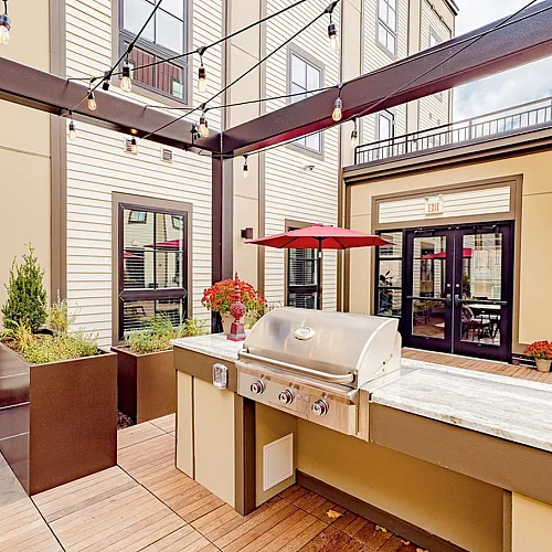 Inviting outdoor patio with a sleek grill station, charming string lights, and cozy seating areas ideal for entertaining.
