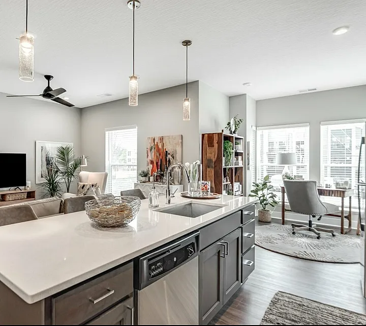Modern open-concept living space featuring a sleek kitchen island, stylish living room, and sunlit dining area.