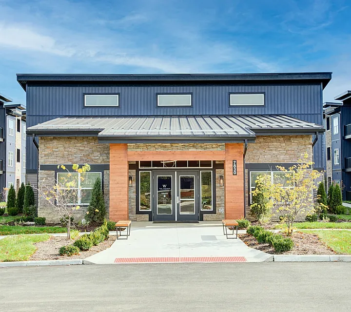 Modern apartment complex showcasing sleek design with stone and wood accents, surrounded by well-manicured greenery and inviting walkways.
