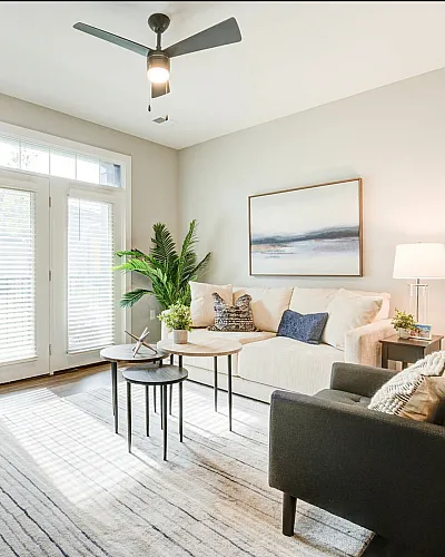 Bright, modern living room with cozy seating, elegant decor, and abundant natural light through large windows.