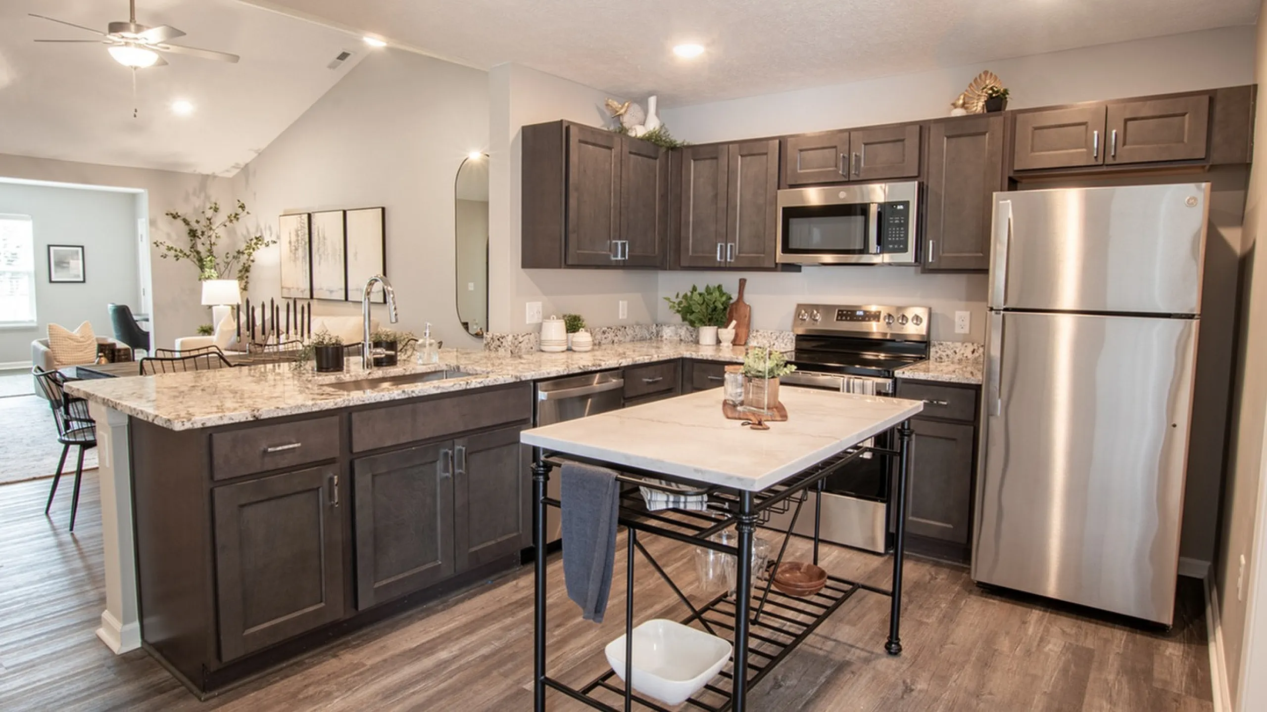 Modern open-concept kitchen with stylish dark cabinets, sleek stainless steel appliances, and a cozy living area perfect for entertaining.