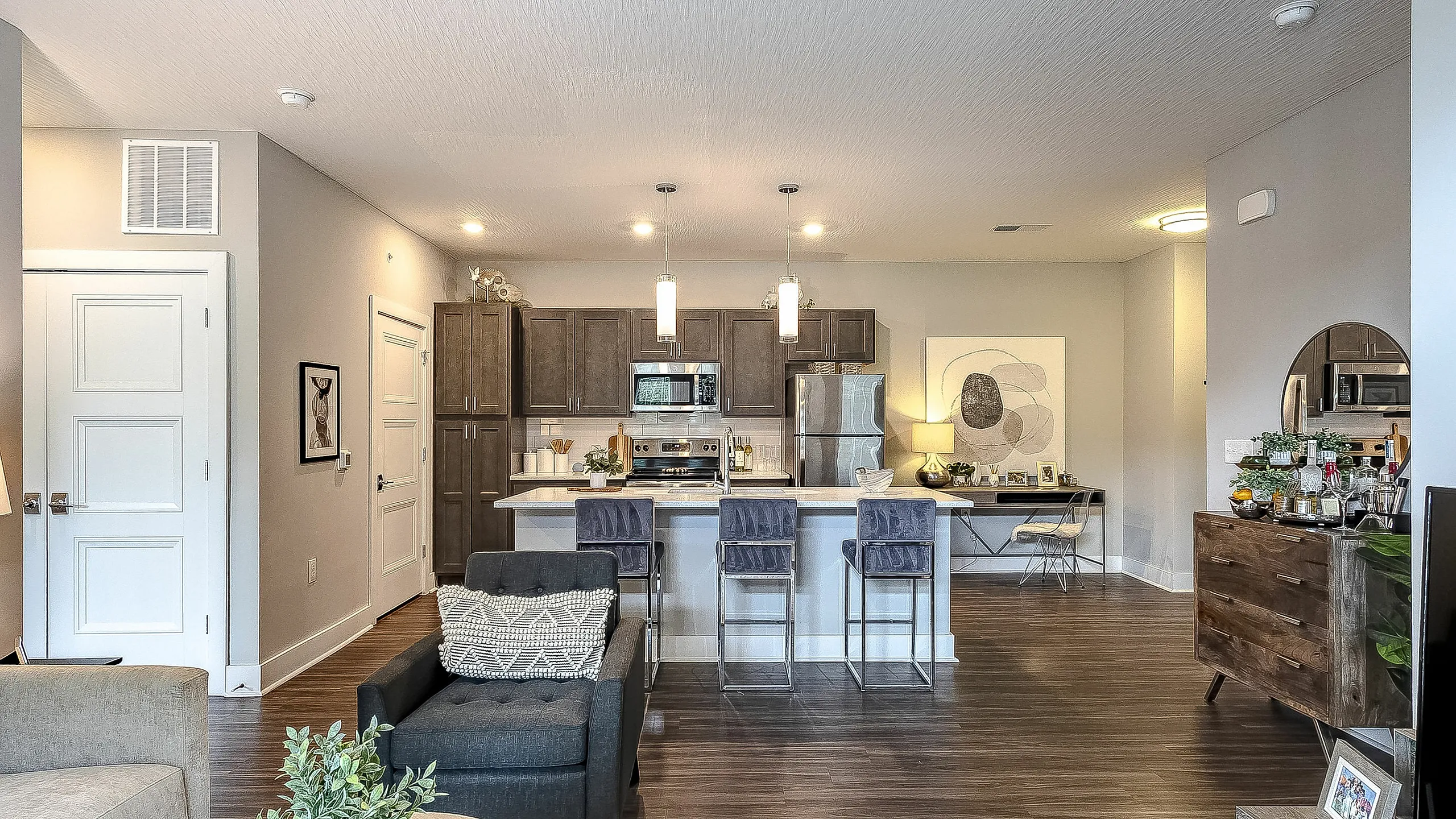 Sophisticated open-concept living area with modern kitchen, stylish bar seating, and chic decor, perfect for entertaining.