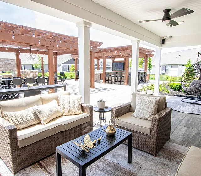Luxurious outdoor patio with cozy seating, modern decor, and elegant pergola, ideal for relaxing and entertaining.