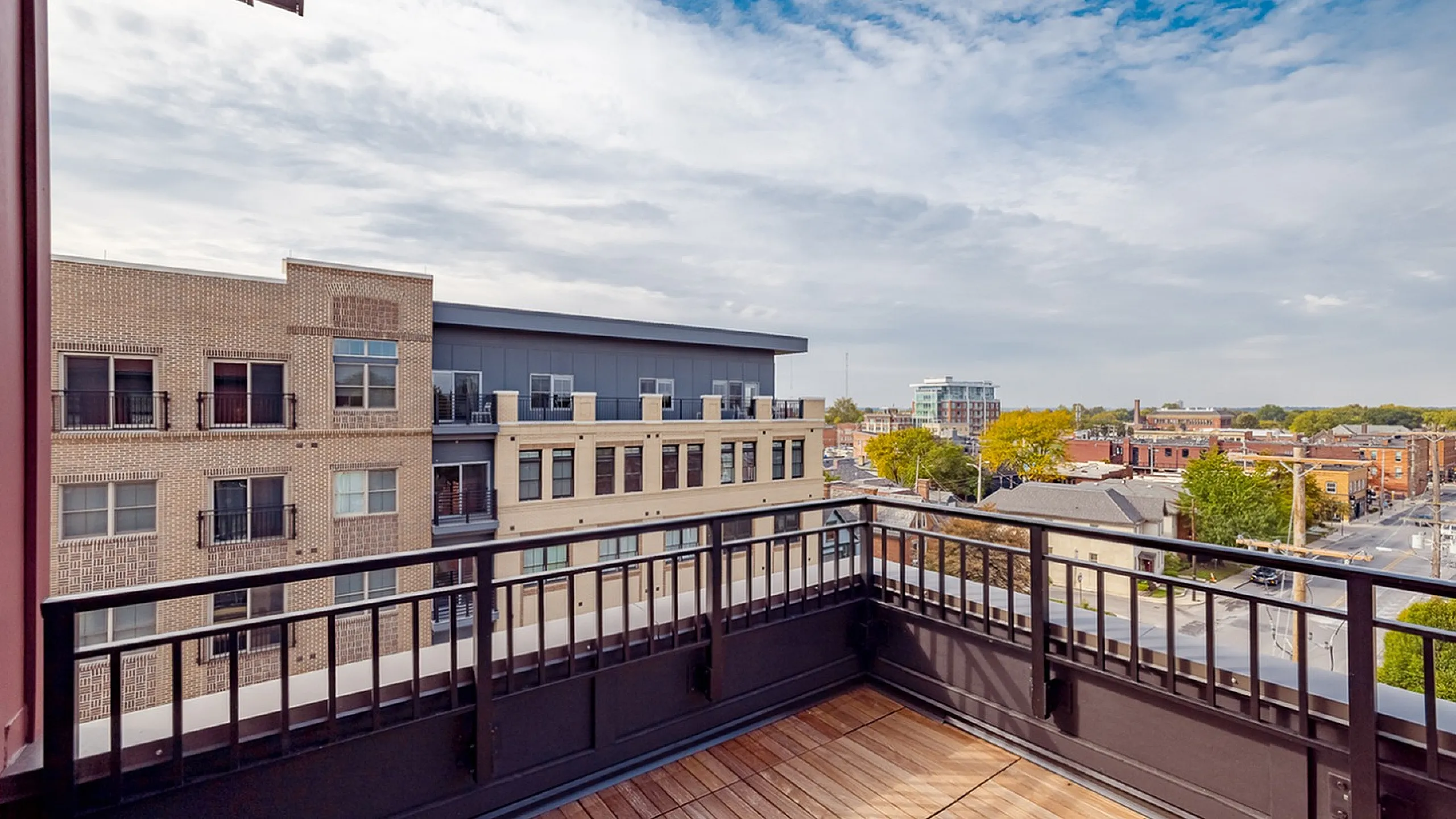 Chic urban rooftop balcony with stylish wooden decking offering panoramic city views.