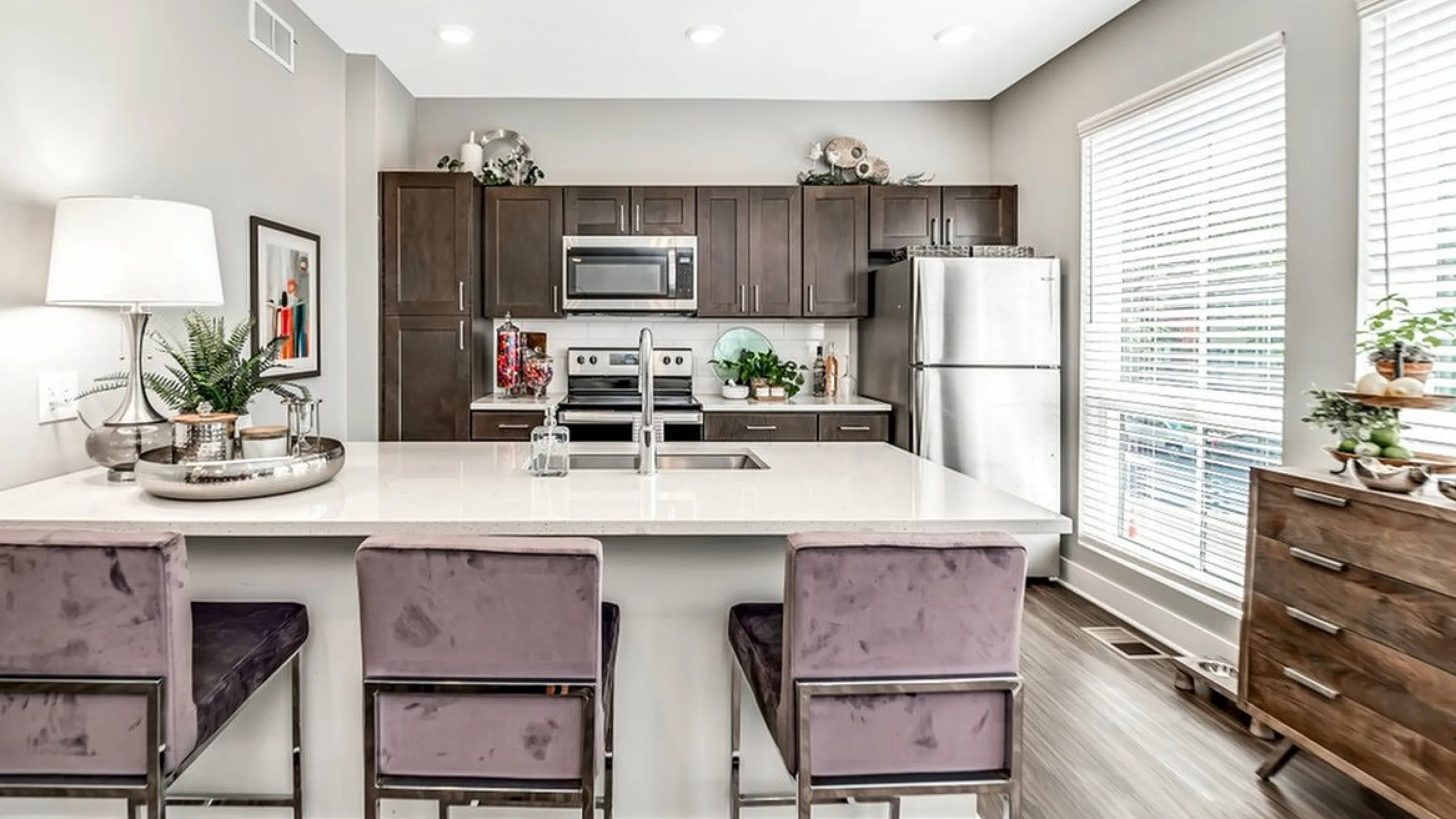 Bright modern kitchen with sleek dark cabinets, stainless steel appliances, and a chic island with plush seating.