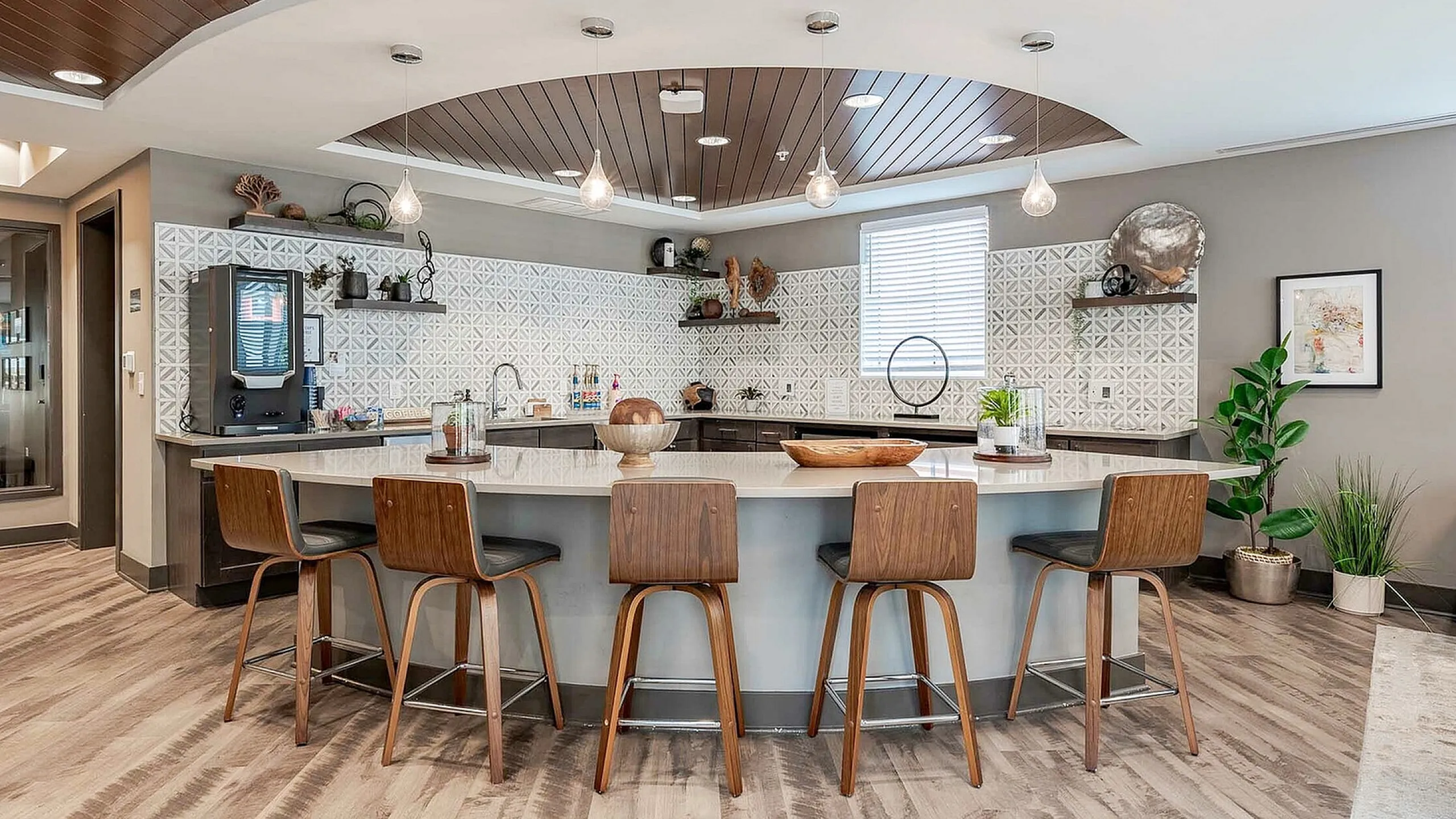 Luxurious and modern kitchen space with elegant wood-paneled ceiling, stylish bar seating, and sleek countertops, ideal for entertaining.