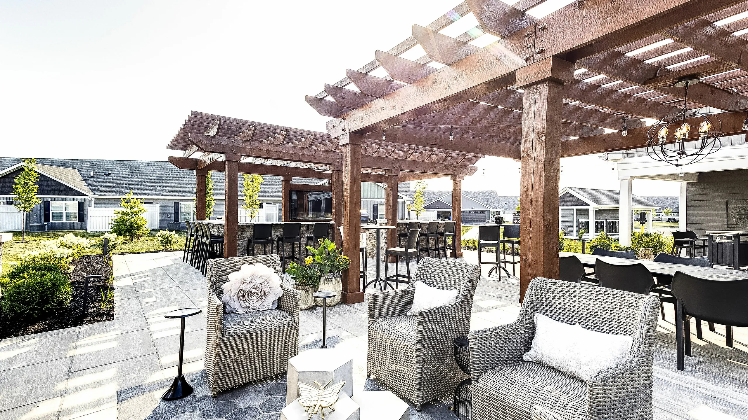 Charming outdoor patio with elegant pergola, stylish wicker chairs, and lush garden views at a modern apartment complex.