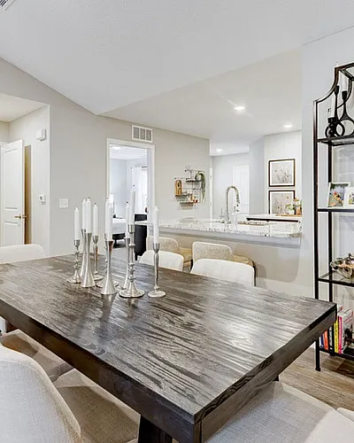 Contemporary dining area with elegant wooden table, modern decor, and open-plan kitchen in a stylish apartment.