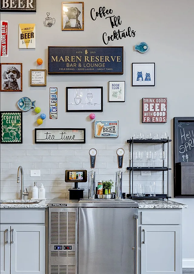 Chic bar lounge area with stylish wall art displaying a mix of beer-themed decor and playful wall signage, complemented by modern furnishings and elegant glassware shelving.