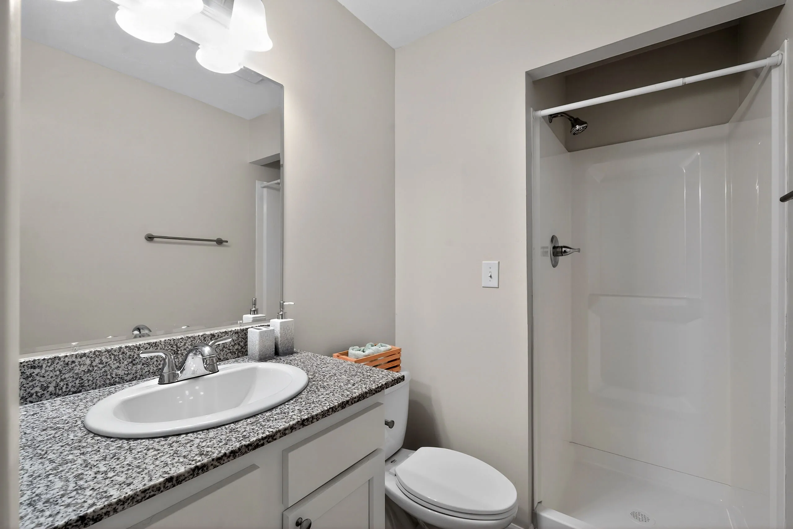 Contemporary bathroom with elegant granite countertop, sleek fixtures, and a spacious walk-in shower.