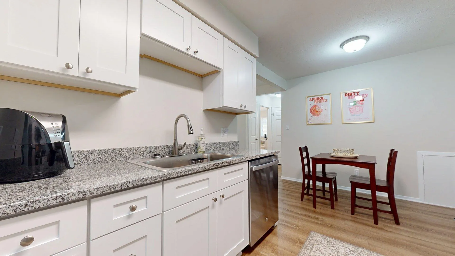 Modern kitchen with sleek granite countertops, stylish white cabinetry, and cozy dining nook featuring elegant art decor.