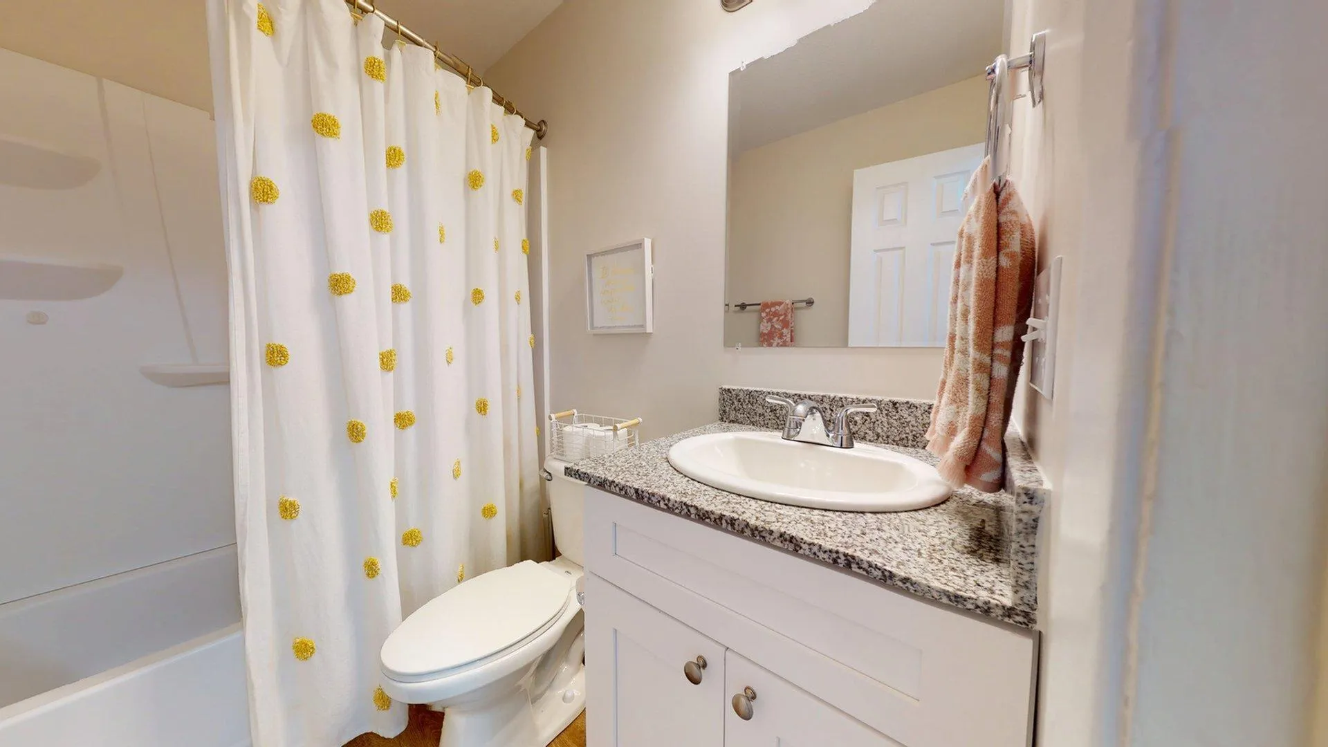 Charming bathroom featuring a granite countertop, modern sink, and a delightful shower curtain with yellow accents.