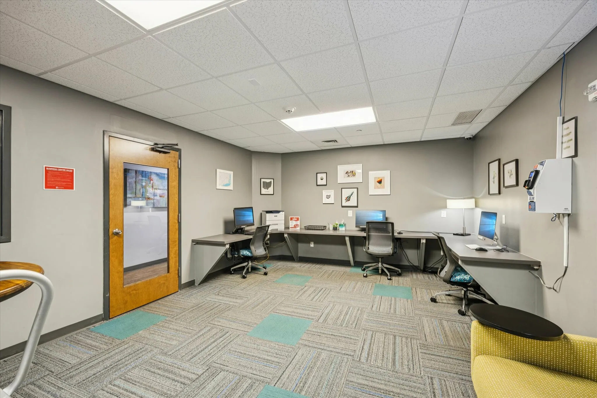 Modern co-working office space with sleek workstations, comfortable chairs, and vibrant decor featuring stunning artwork.