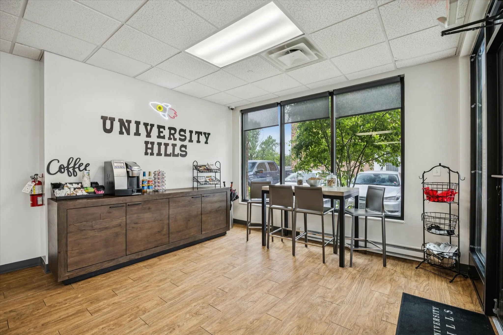 Inviting University Hills lobby featuring a cozy coffee station, elegant high chairs, and expansive windows with lush views.