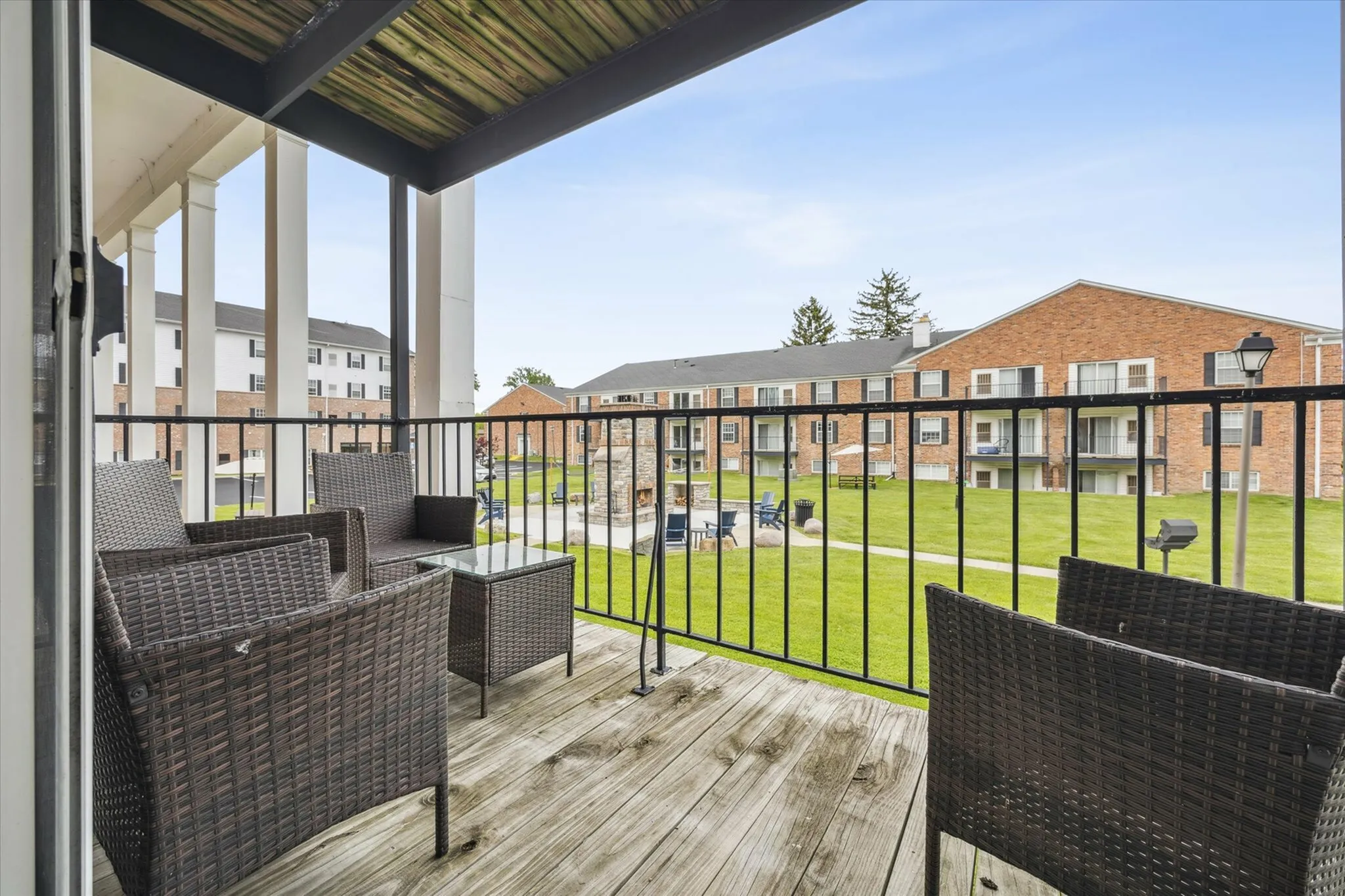 Charming balcony view overlooking well-manicured green lawns with stylish rattan furniture, perfect for relaxation and outdoor gatherings.
