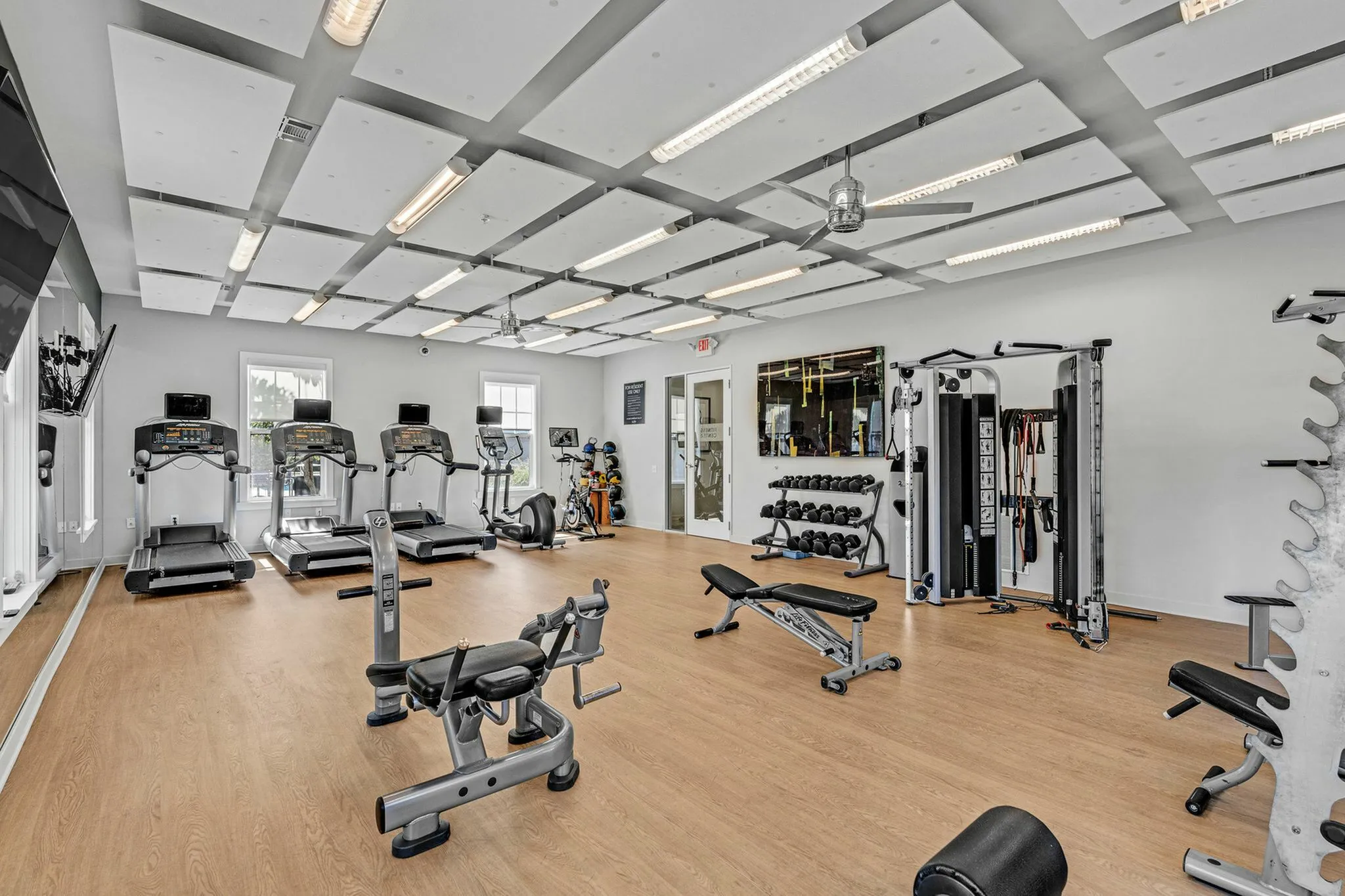 Modern fitness center featuring state-of-the-art equipment, including treadmills, weight machines, and a cycling area with ample natural light.