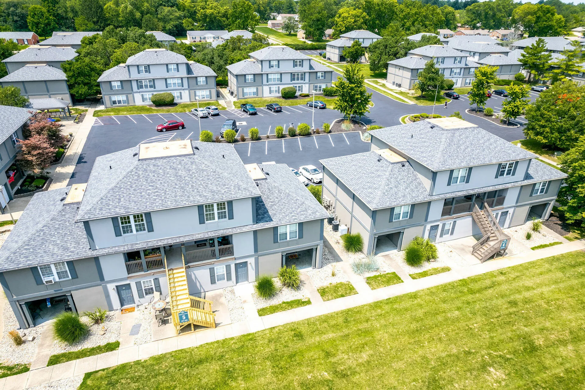 Charming residential complex with modern two-story buildings surrounded by lush greenery and ample parking space.