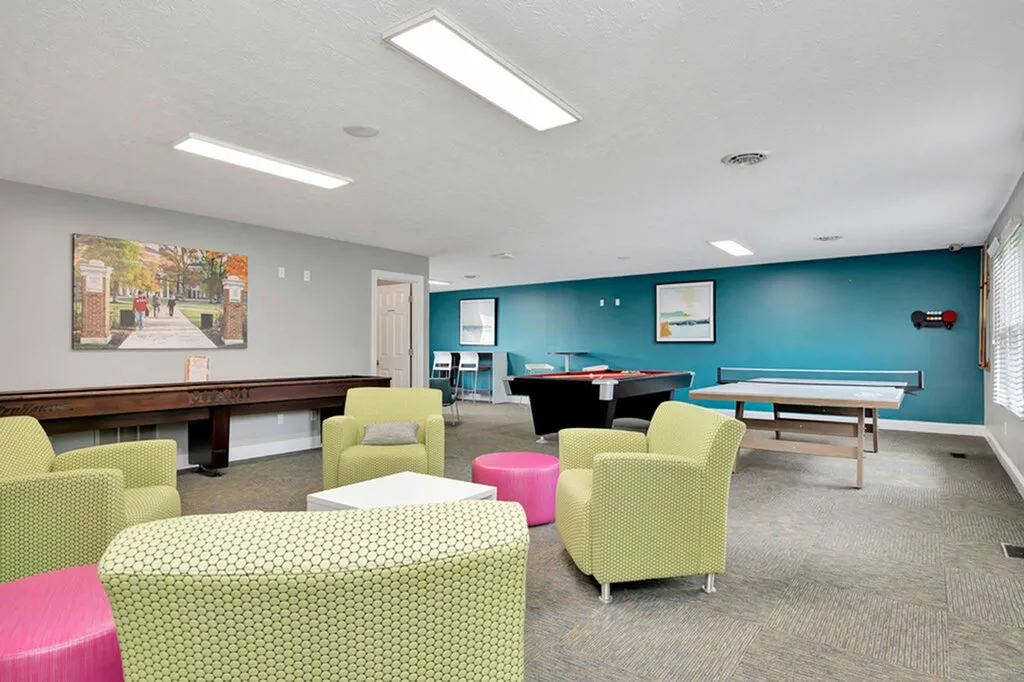 Vibrant community game room featuring modern seating, pool table, ping pong, and shuffleboard under bright lighting.