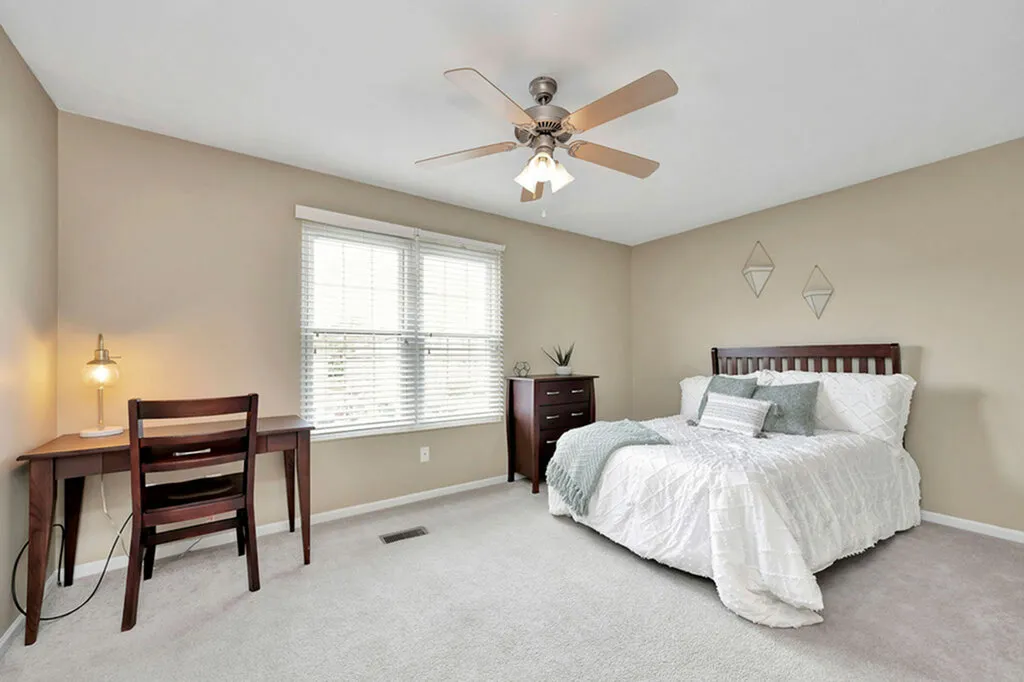 Inviting bedroom with modern decor featuring a cozy bed, elegant desk with ambient lighting, and a soothing neutral palette.