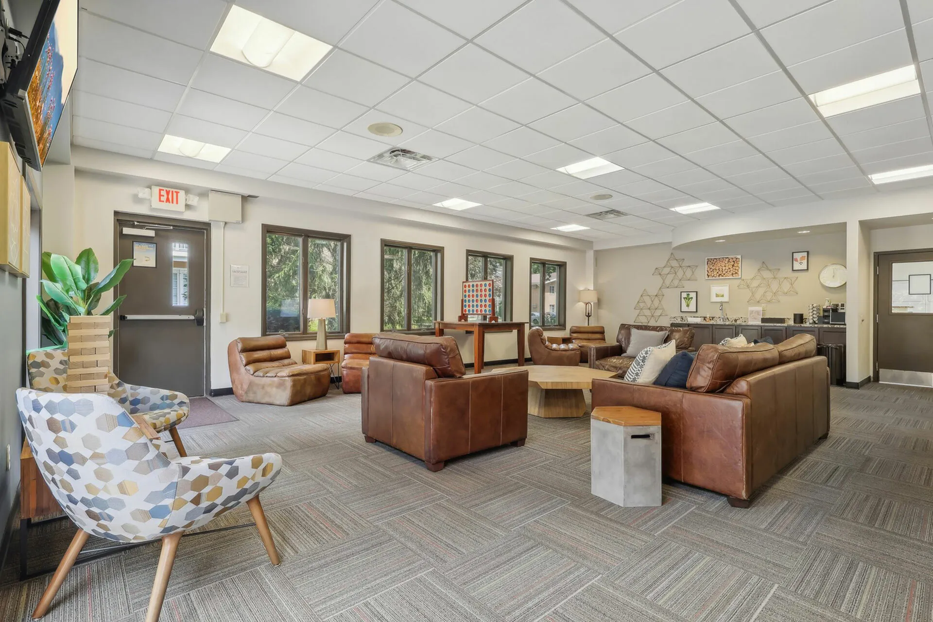 Inviting communal lounge with contemporary leather seating, accented by natural light through large windows and modern geometric decor.