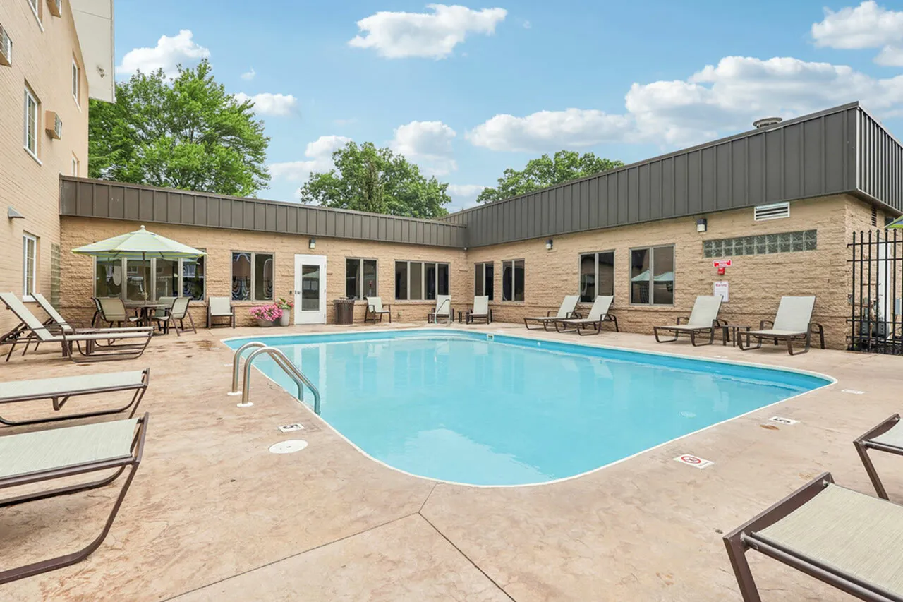 Inviting outdoor pool area with lounge chairs and umbrella seating, perfect for relaxation and summer enjoyment.