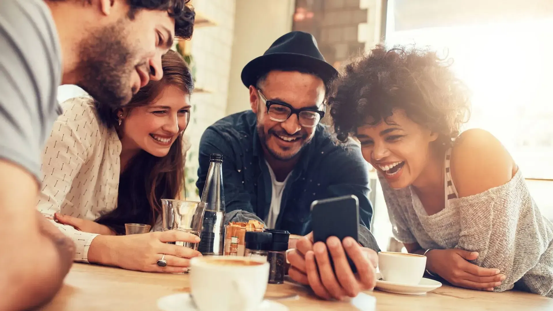 Group of friends drinking coffee looking at a mobile phone