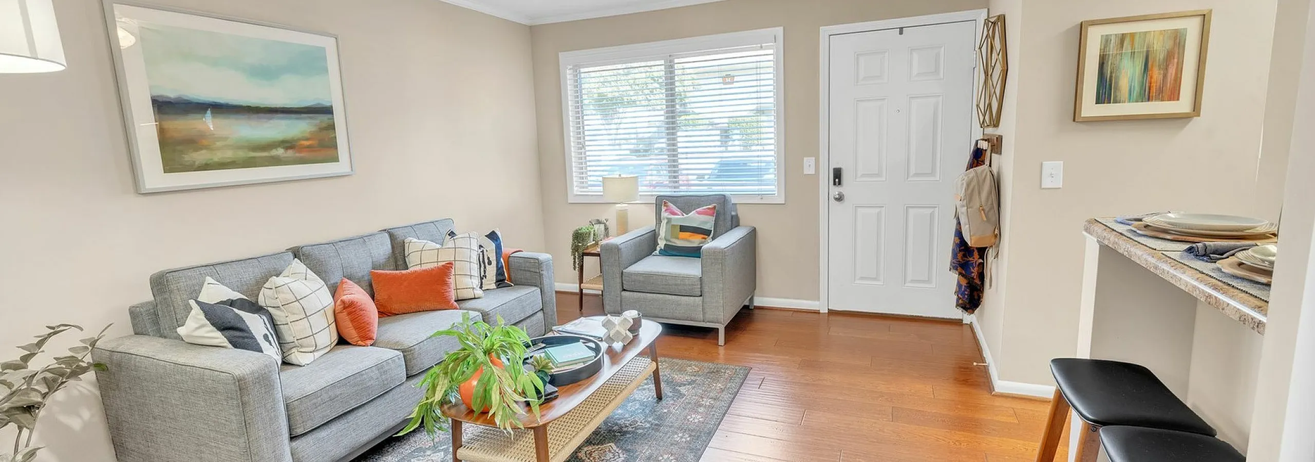 Bright and inviting living room featuring modern gray couches, colorful cushions, and a stylish coffee table, perfect for relaxed entertaining.