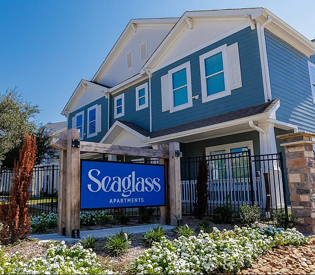 Charming blue Seaglass Apartments showcasing a modern design, lush landscaping, and inviting curb appeal.