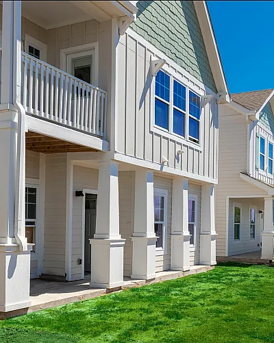 Charming townhouse with elegant balconies and lush green lawn under a bright blue sky.
