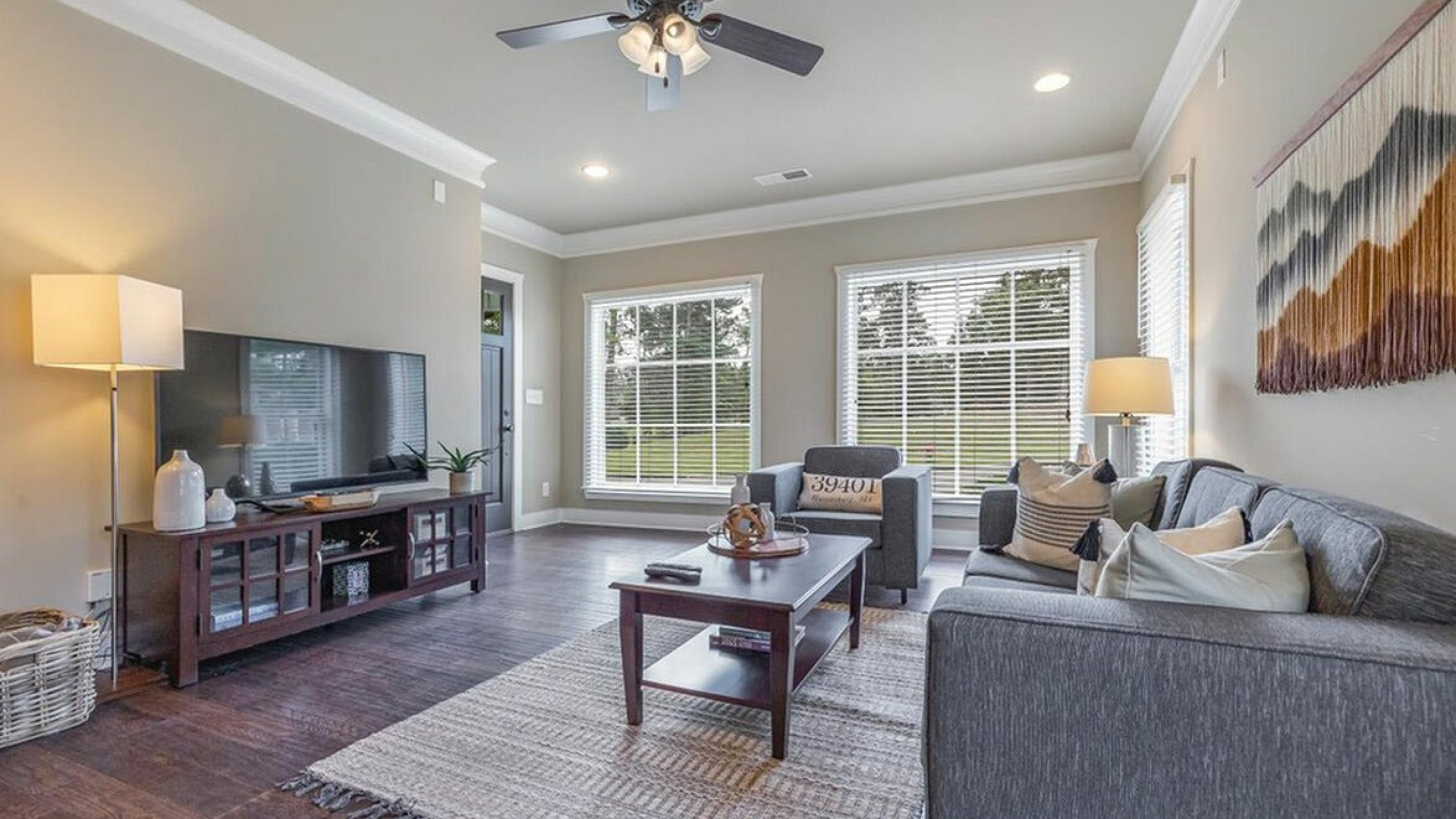 Inviting living room with cozy sofa, sleek television setup, and large windows offering abundant natural light.
