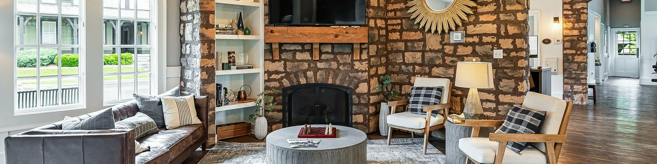 Charming living room with rustic stone walls, cozy seating, and a warm fireplace, featuring elegant decor and natural light.
