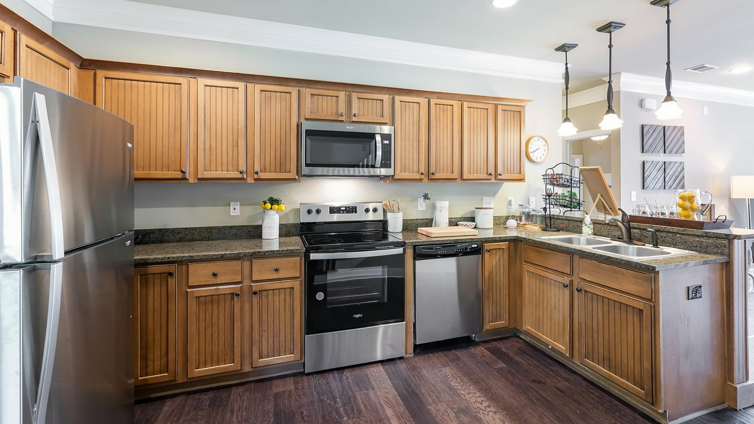 Charming kitchen with warm wooden cabinetry, modern stainless steel appliances, and pendant lighting, perfect for culinary enthusiasts.