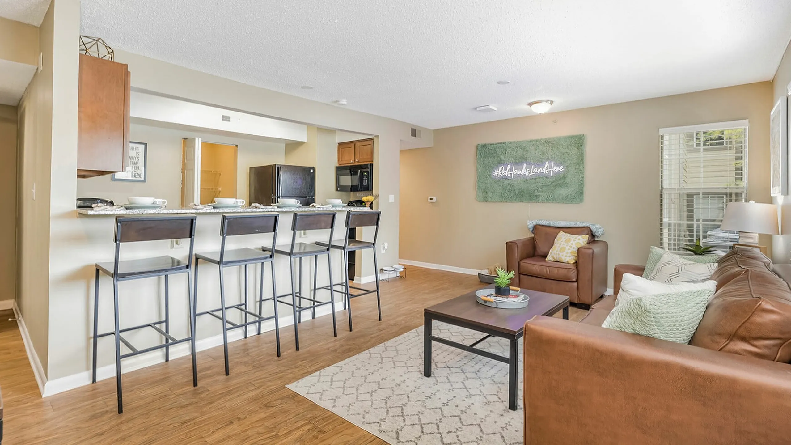 Inviting living space with elegant hardwood floors, cozy seating area, and a stylish breakfast bar with modern stools.