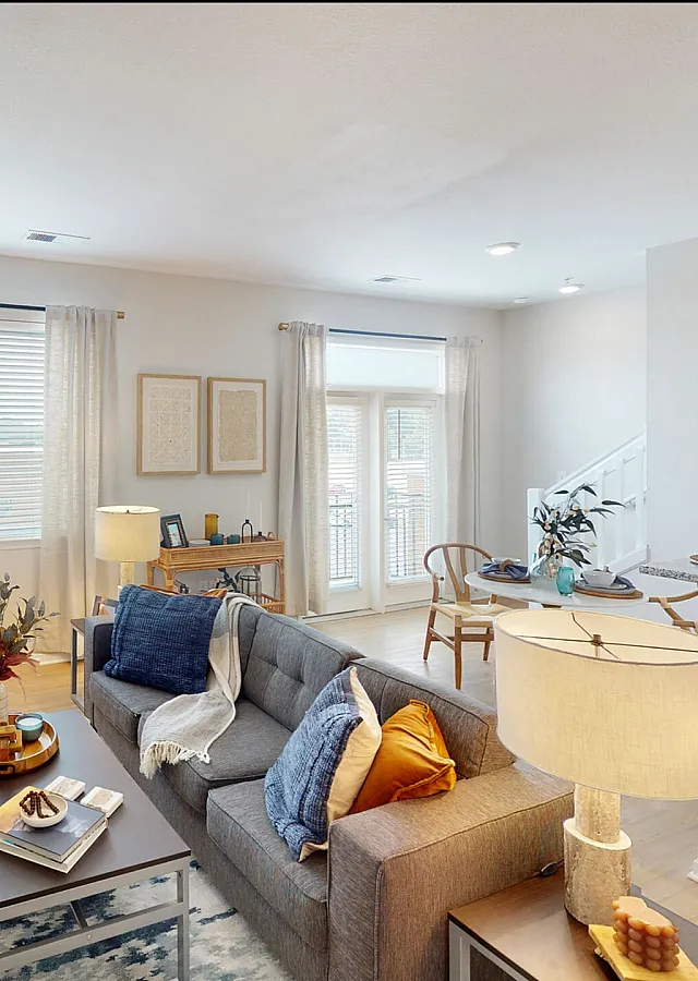 Bright and inviting living space featuring stylish decor, natural light through large windows, and a modern open-plan kitchen.