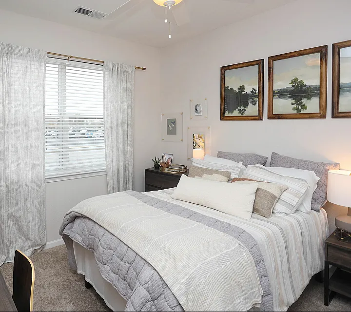Cozy and inviting bedroom featuring a comfortable bed, elegant decor, and ample natural light through large windows, ideal for relaxation.