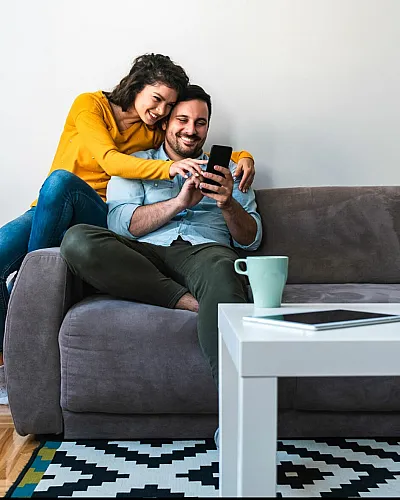Cozy living room with a couple enjoying a moment on a plush gray sofa, accented by vibrant cushions and a stylish coffee table.