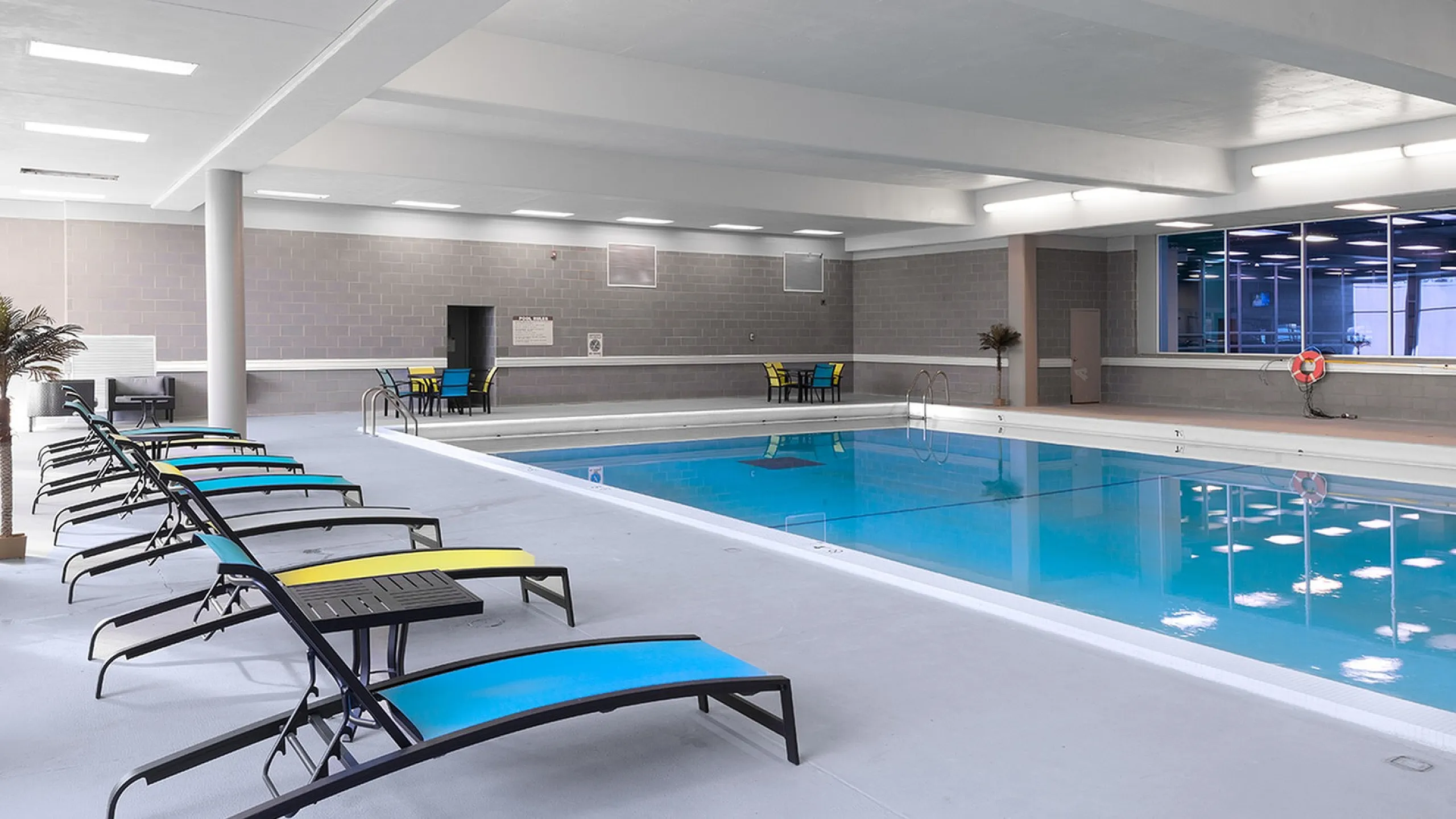 Luxurious indoor pool area with sleek lounge chairs and vibrant lighting, perfect for relaxation and recreation.