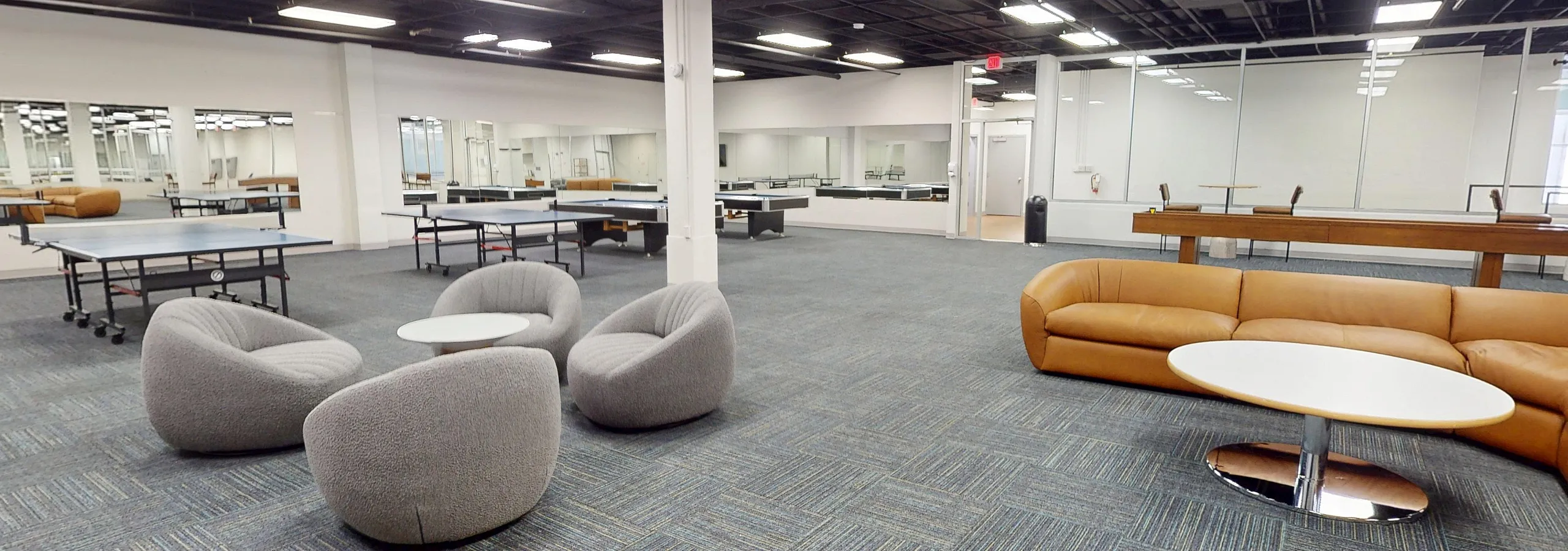 Spacious and modern recreational area featuring chic seating, ping-pong tables, and elegant flooring. Perfect for relaxation and entertainment.