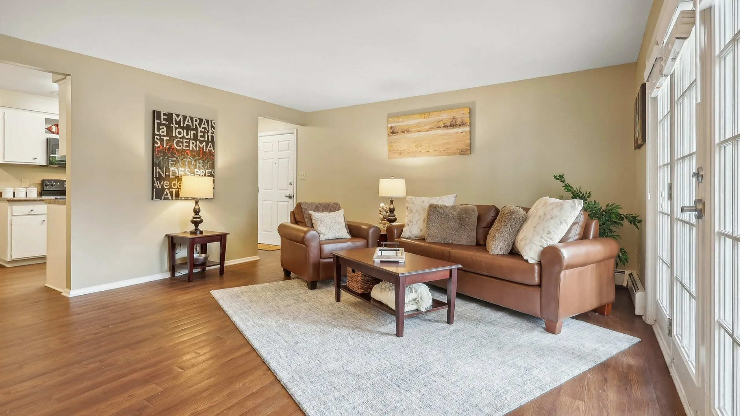 Inviting living room with plush leather furniture, cozy decor, and natural light streaming through large French doors.