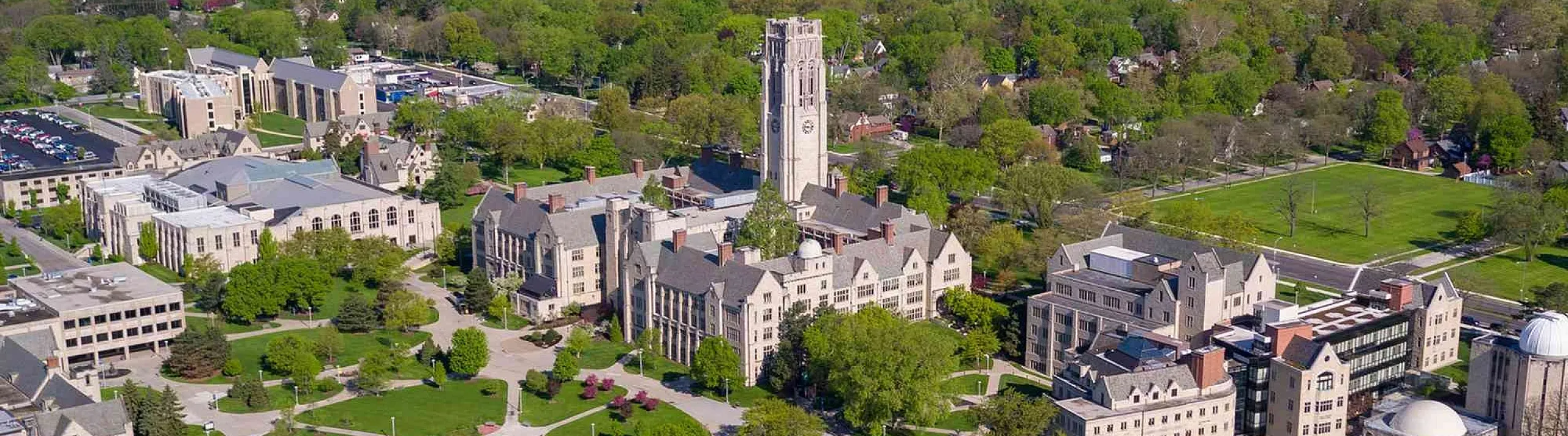 Vibrant aerial view of a picturesque college campus featuring historic buildings surrounded by lush greenery.